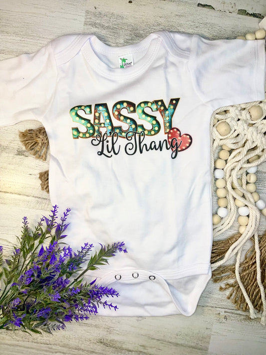 Product details  Custom sublimated  onesie that reads "Sassy Lil Thang" Pressed on a Laughing Giraffe Short sleeve  Fits true to size Contact us about a custom color shirt.   *Colors may vary slightly due to monitor resolution and lighting* Southern Bliss Boutique